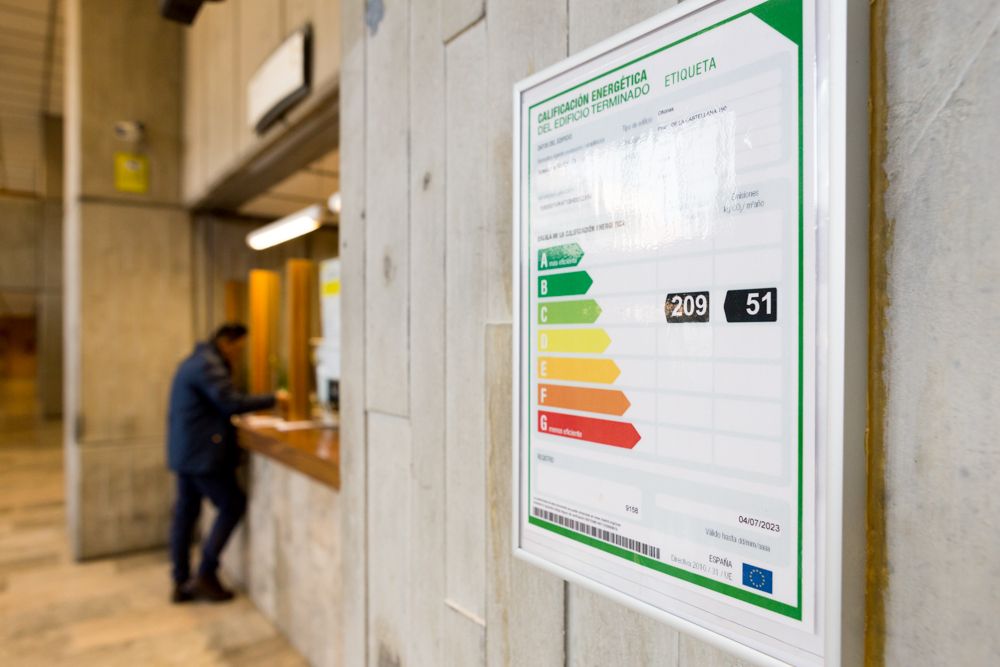 Primer plano de la etiqueta de calificación energética del edificio terminado instalada en el hall de acceso del MITECO